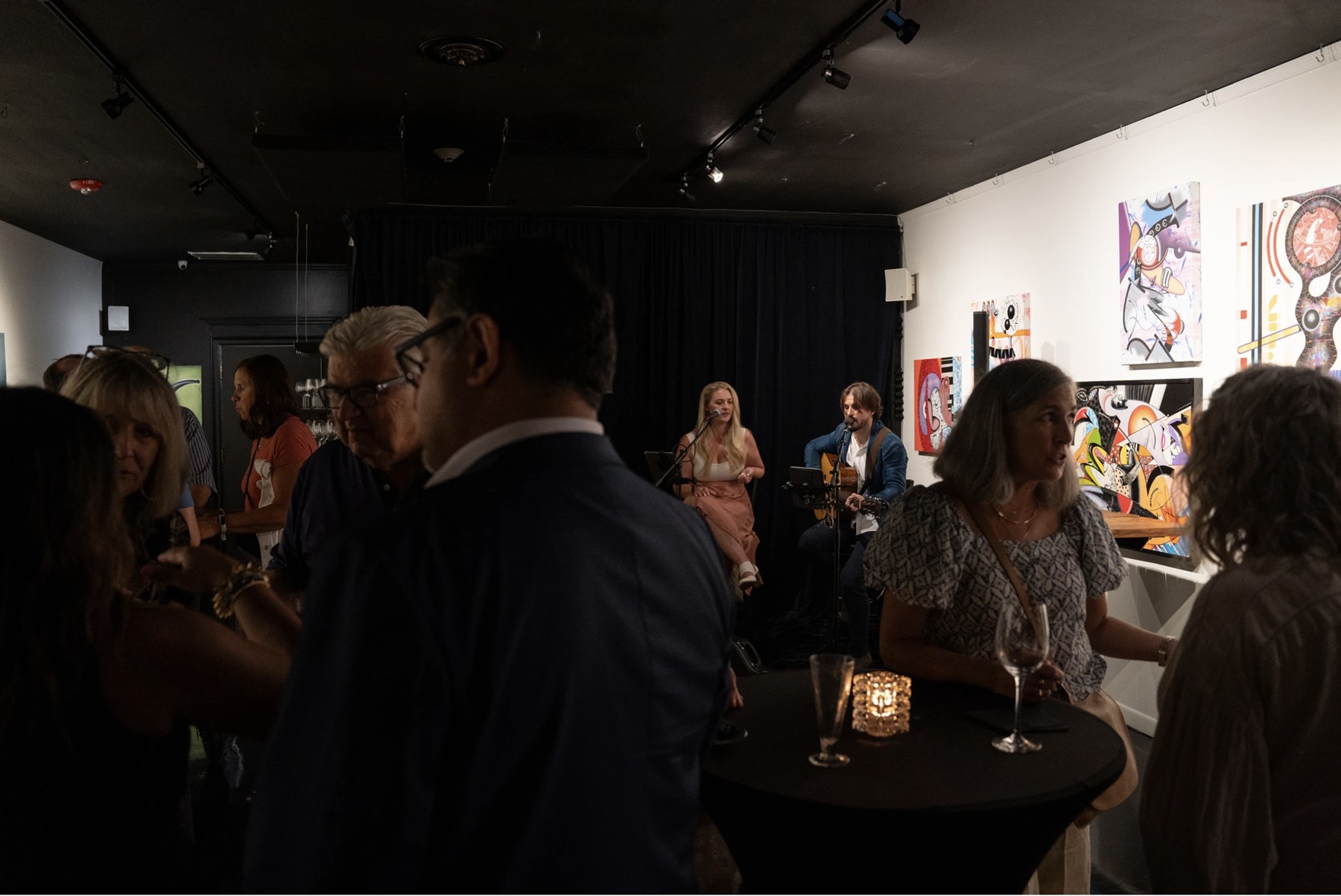 Guests mingling at a cocktail reception inside The Gallery, with original art on the walls